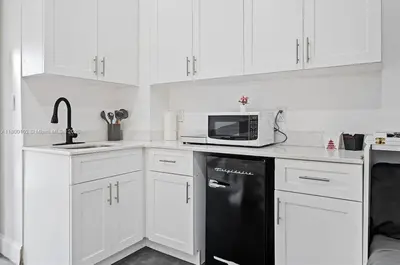 a kitchen with white cabinets and a black refrigerator at Studio in Design District in Miami