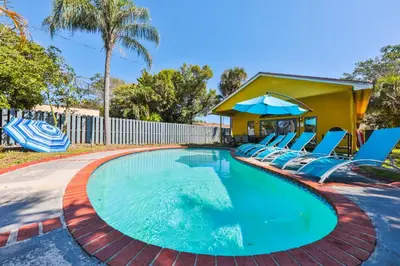 a swimming pool with chairs and an umbrella at Zero Mile Villa Start your journey in Hollywood