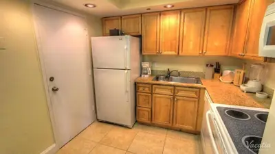 a kitchen with a white refrigerator and wooden cabinets at 2 BR-11th Floor Corner Unit - Fort Lauderdale Beach Resort in Fort Lauderdale