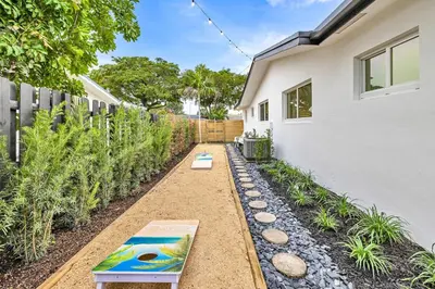 a garden with a bench next to a house at Tropical Bliss 15 Min to Beach in Plantation