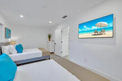 a bedroom with a bed and a tv on a wall at Tropical Bliss 15 Min to Beach in Plantation