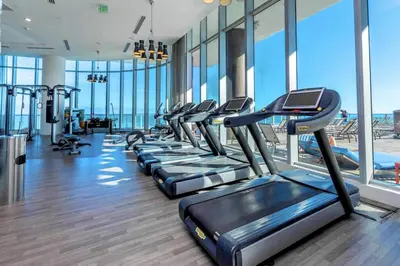 a row of treadmills in a gym with windows at Oceanfront Escape - Rooftop Pool & Beach Access in Hollywood