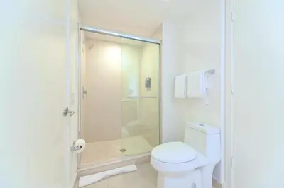 a white bathroom with a shower and a toilet at Oceanfront Escape - Rooftop Pool & Beach Access in Hollywood