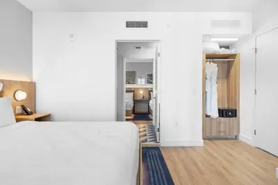 a bedroom with a white bed and a hallway at City-View Condo W Pool Access & Free Parking in Miami