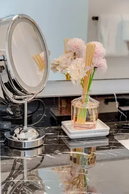 a mirror and a vase of flowers on a counter at Sky Corner Residence- Pool Parking Amenities in Miami