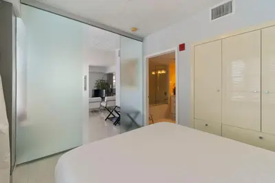 a bedroom with a white bed and a glass wall at South Beach, Perfect Oceanfront Apartment, Iconic Art Deco Building, Walk to Everything! in Miami Beach