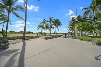 a sidewalk in a park with palm trees at South Beach, Perfect Oceanfront Apartment, Iconic Art Deco Building, Walk to Everything! in Miami Beach