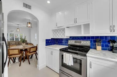 a kitchen with white cabinets and a dining room with a table at Spacious & Stylish 2BR Retreat near Victoria Park in Fort Lauderdale