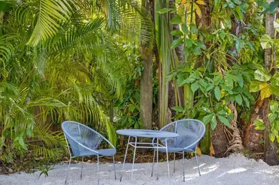 two blue chairs and a table in front of trees at Spacious & Stylish 2BR Retreat near Victoria Park in Fort Lauderdale