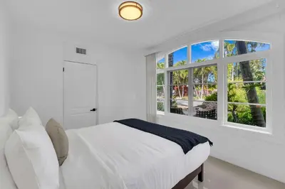 a white bedroom with a bed and a window at Spacious & Stylish 2BR Retreat near Victoria Park in Fort Lauderdale