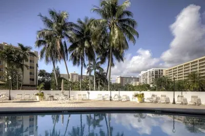 a pool with palm trees and chairs and buildings at Le Frontenac 204 STR-01054 in Sunny Isles Beach