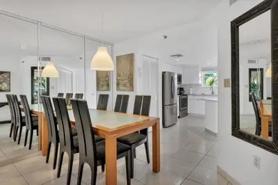 a dining room and kitchen with a wooden table and chairs at Le Frontenac 204 STR-01054 in Sunny Isles Beach