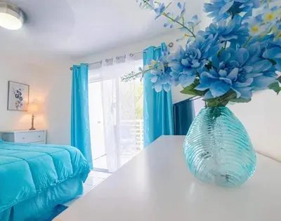 a vase with blue flowers on a table in a bedroom at Le Frontenac in Sunny Isles unit 402 STR-03003 in Sunny Isles Beach