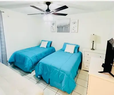 two blue beds in a room with a ceiling fan at Le Frontenac in Sunny Isles unit 402 STR-03003 in Sunny Isles Beach