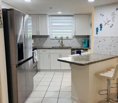 a kitchen with white cabinets and a stainless steel refrigerator at Le Frontenac in Sunny Isles unit 402 STR-03003 in Sunny Isles Beach