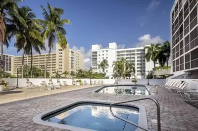 a resort swimming pool with palm trees and buildings at Le Frontenac 414 STR-01532 in Sunny Isles Beach