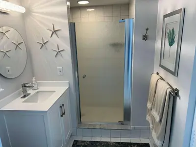 a bathroom with a shower with a sink and a mirror at Le Laurier in Sunny Isles Beach