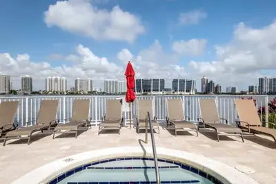 a pool with lounge chairs and a red umbrella at Le Marina Bay 1001 STR-01504 in Sunny Isles Beach