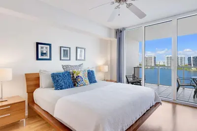 a white bedroom with a bed and a balcony at Le Marina Bay 1004 STR-02738 in Sunny Isles Beach