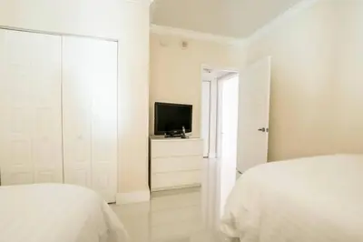 a white bedroom with two beds and a television at Le Marina Bay 1006 STR-01435 in Sunny Isles Beach