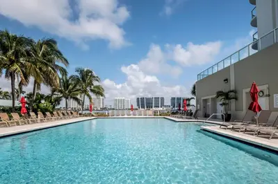 a swimming pool at a resort with chairs and palm trees at Le Marina Bay 1006 STR-01435 in Sunny Isles Beach