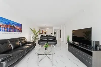 a living room with black leather couches and a tv at Marina Bay Club STR-0 in Sunny Isles Beach