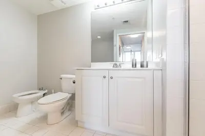 a white bathroom with a toilet and a sink at Le Marina Bay 403 STR-01408 in Sunny Isles Beach