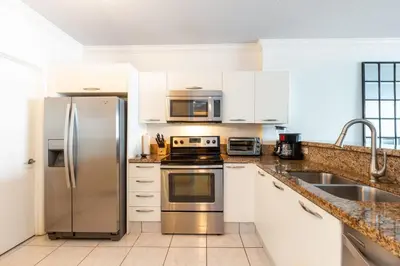 a kitchen with stainless steel appliances and white cabinets at Le Marina Bay 409 STR -02439 in Sunny Isles Beach