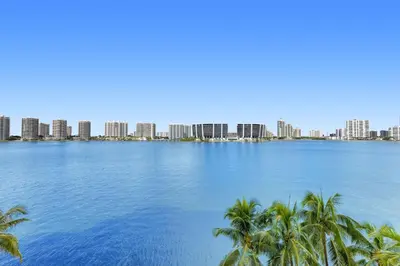 a view of the city from the shore of a lake with palm trees at Le Marina Bay 505 STR-02744 in Sunny Isles Beach
