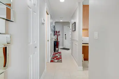 a hallway with white walls and a red rug on the floor at Le Marina Bay 505 STR-02744 in Sunny Isles Beach
