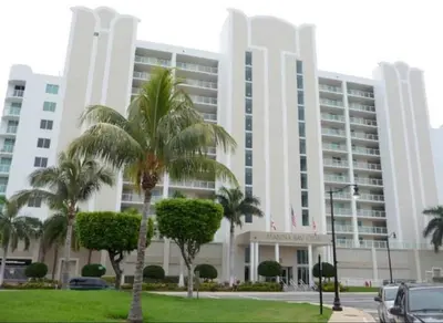 a large building with palm trees in front of it at Le Marina Bay 701 STR-01254 in Sunny Isles Beach