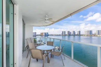 a balcony with a table and chairs and a view of the water at Le Marina Bay 801 STR-01477 in Sunny Isles Beach