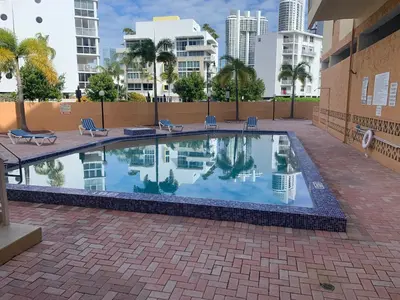 a swimming pool with chairs and buildings in the background at Le Marbella 303 STR-02828 in Sunny Isles Beach