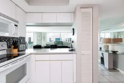 a kitchen with white cabinets and a living room at Le Montcalm 804 STR-01923 in Sunny Isles Beach