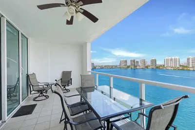 a balcony with chairs and a glass table with a view of the water at Le Marina Bay PH3 STR-01487 in Sunny Isles Beach