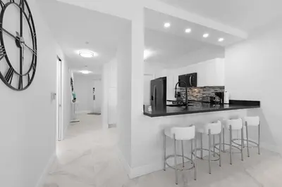 a kitchen with a bar with stools and a clock at Le Marina Bay PH3 STR-01487 in Sunny Isles Beach