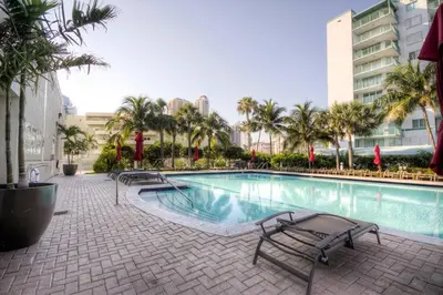 a swimming pool with chairs and palm trees and buildings at Le Marina Bay PH5 STR-01500 in Sunny Isles Beach