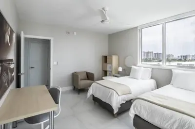 a bedroom with two beds and a desk and a window at Le Marina Bay 810 STR-01434 in Sunny Isles Beach