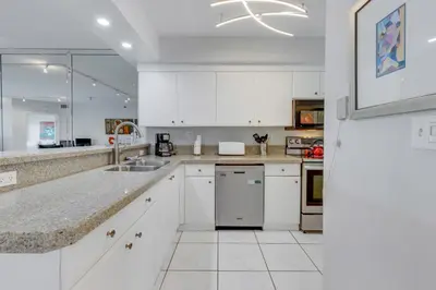 a white kitchen with white cabinets and appliances at Les Pelicans #316 STR-02743 in Sunny Isles Beach