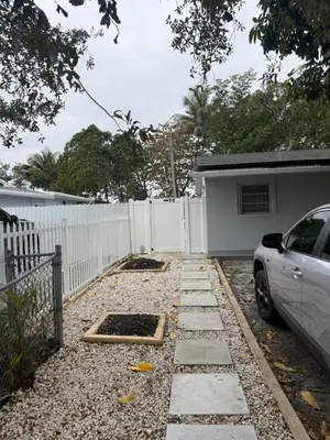 a driveway of a house with a white fence at Modern private efficiency Miami Gardens in Miami Gardens