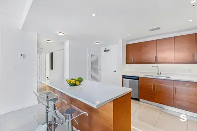 a kitchen with wooden cabinets and a bowl of fruit on the counter at Modern 2-BD Condo in Midtown Miami Pool & Gym in Miami