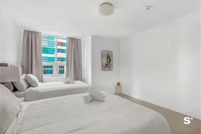 a white bedroom with two beds and a window at Modern 2-BD Condo in Midtown Miami Pool & Gym in Miami