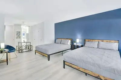 a bedroom with two beds and a blue wall at Beachside Escape with King Bed plus 2 Queens Miami in Miami Beach