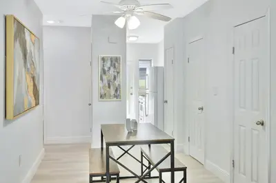 a white hallway with a table and a ceiling fan at Beachside Escape with King Bed plus 2 Queens Miami in Miami Beach