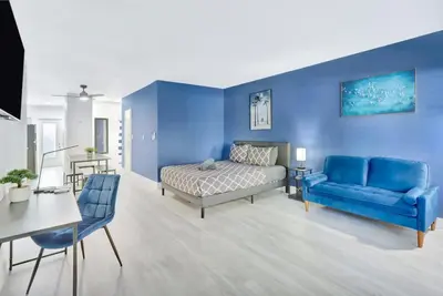 a bedroom with a bed and a blue wall at Bright 1BR Miami Beach Apt with 3 Queens & Smart TV in Miami Beach