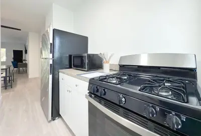 a kitchen with a black stove and a refrigerator at Bright 1BR Miami Beach Apt with 3 Queens & Smart TV in Miami Beach