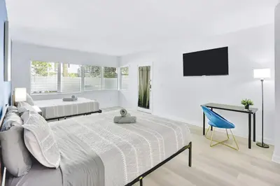 a white bedroom with a large bed and a desk at 1BR Miami Beach Apt with King plus 2 Queens & Smart TV in Miami Beach