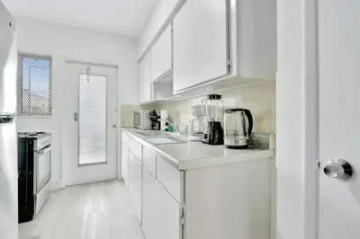 a white kitchen with white cabinets and a sink at 1BR Miami Beach Apt with King plus 2 Queens & Workspace in Miami Beach