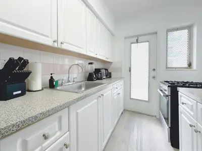 a white kitchen with white cabinets and a sink at 1BR Miami Beach Apt with 3 Queens plus Free Parking in Miami Beach