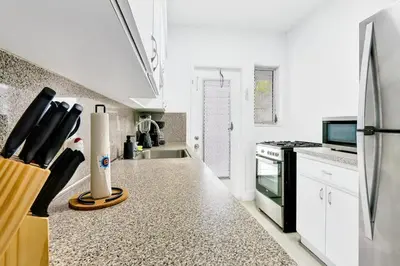 a kitchen with white cabinets and a counter with a refrigerator at Bright 1BR Miami Beach Stay Near the Ocean in Miami Beach